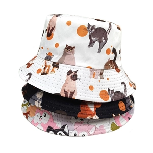 Three stacked reversible bucket hats with cute cartoon cat patterns in white, black and pink