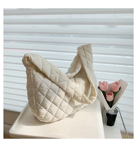 Close-up of cream quilted puffer shoulder bag with a soft cloud texture and floral accents