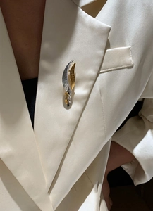 Macro detail of leaf-shaped brooch with gold and silver finish and micro-inlaid zircon