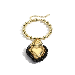 Detailansicht des Sacred-Heart-Anhängers und der goldenen Perlen am Vintage-Armband