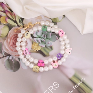 Detail showing two pearl bracelets with colorful clay animal charms and gold clasps