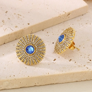 Detail of gold titanium stud earring featuring blue gemstone and radiant crystal sunflower design