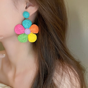 Close-up of colorful woven flower earring with vibrant petals and natural fiber texture