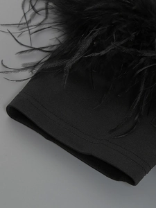 Close-up of black bandage fabric with soft feather trim on a sexy off-shoulder dress