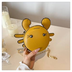 Detail of yellow crab-shaped mini bag with litchi texture and gold chain strap