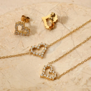 Elegant gold heart jewelry set with clear crystals on a marble stone tray