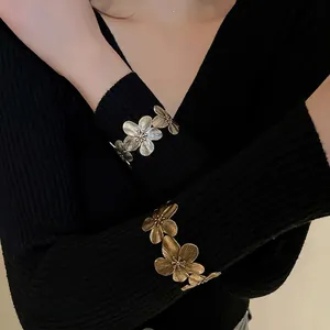 Vintage gold flower cuff bracelet with brushed petal texture on elegant model display