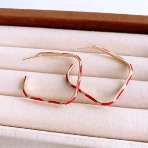 Fashionable wave square enamel drop oil earrings in red and gold finish on beige velvet