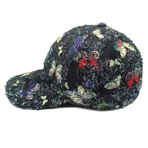 Dettaglio cappello nero con farfalle colorate e particolare trama in rilievo