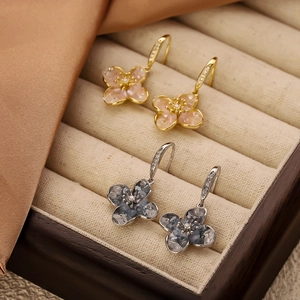 Elegantes pendientes de flores con circón rosa y azul en un joyero de terciopelo beige