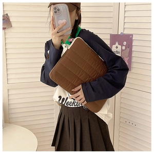 Brown quilted laptop sleeve with soft horizontal textures shown in a lifestyle mirror selfie