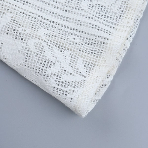 Vue rapprochée de la texture du tissu en dentelle blanche et des motifs de maille