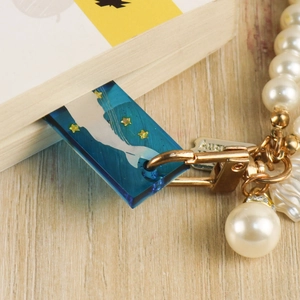 Blue resin heart bookmark with whale tail and gold stars resting on a book page
