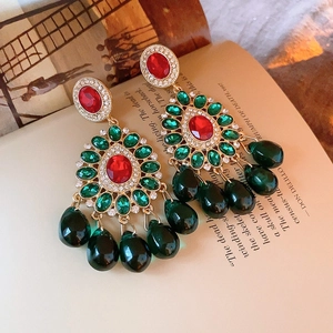 Detail view of vintage gold earrings with red and green gemstones on a book