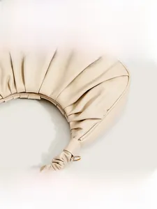 Close-up of ruched cream cloud bag showing fine pleated PU leather texture and gold metal rings
