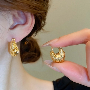 Detailed macro view of gold-plated U-shaped earrings with spiral croissant texture