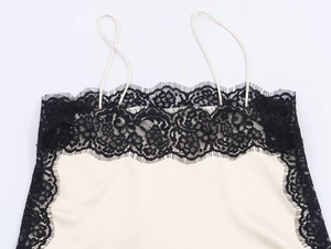 Detail showing delicate floral black lace trim and beige satin fabric on the neckline