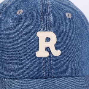Close-up of blue denim baseball cap featuring a white 3D letter R embroidery detail