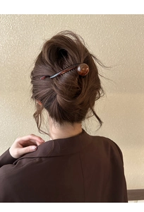 Détail d'une épingle à cheveux écaille marron foncé avec perle ronde dans un chignon