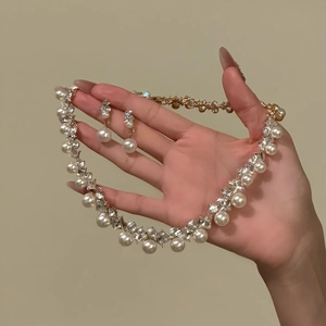 Elegantes goldenes Schmuckset mit Rauten-Diamanten und Perlen von Hand gehalten