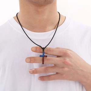 Close-up of a titanium steel cross necklace with red and blue stripes on a male model