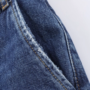 Détail de jean bleu foncé avec surpiqûres orange et bord effiloché sur la poche latérale