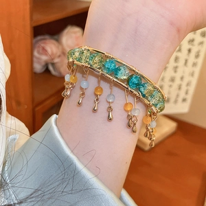 Détail du bracelet multi-rangs avec perles de verre vertes et breloques dorées en gouttes