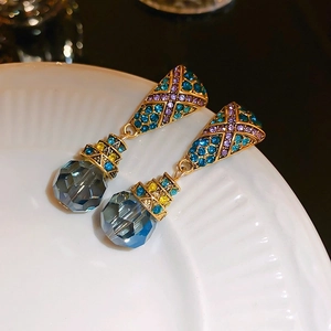 Vue macro de boucles d'oreilles vintage dorées avec strass colorés et cristaux bleus