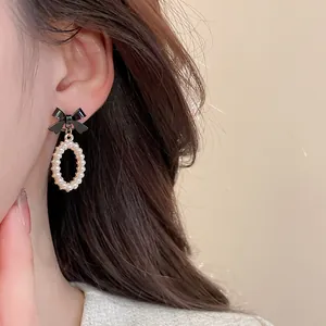Detail of vintage bow pearl drop earrings showing textured pearls and black bow on ear