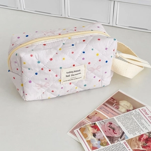 Close-up of quilted makeup bag with pink bow pattern and golden metal zipper detail