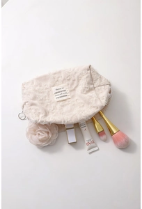 Detailed view of beige corduroy makeup bag with lace overlay and beauty accessories inside