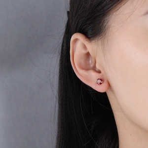 Close-up of minimalist S925 sterling silver stud earring with round red zircon inlay