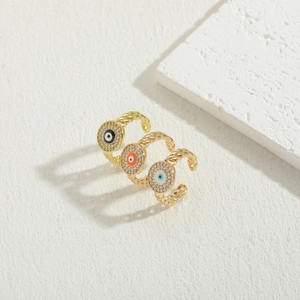 Luxurious 14K gold plated evil eye rings set with colorful zircons on stone background