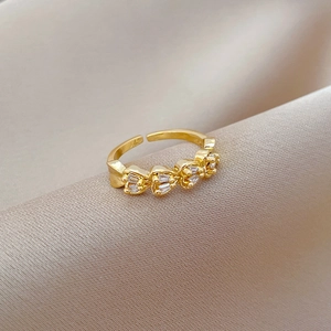 Detail of adjustable gold ring with four heart-shaped crystals on luxury silk background
