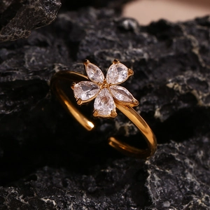 Detailed view of gold five-petal flower ring with pear-cut zircon on dark volcanic rock