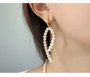 Detailed close-up of French-style Baroque pearl drop earrings on model's ear