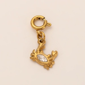 Macro detail of 18K gold-plated crab pendant featuring a sparkling clear gemstone