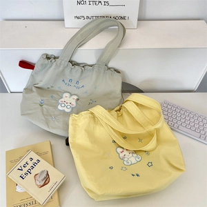 Detail of embroidered drawstring tote bags with cute bunny patterns in light green and yellow
