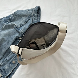 Cream nylon shoulder bag with large capacity shown with daily items on denim
