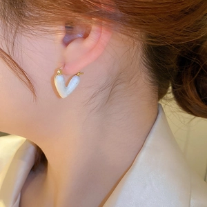 Gros plan détaillé d'une boucle d'oreille cœur en perle avec placage or sur un mannequin