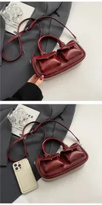 Detail view of burgundy saddle bag with twin front pockets and silver hardware accent