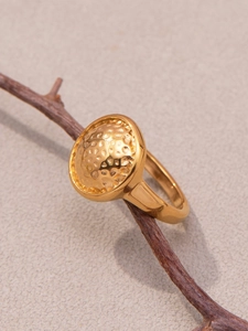 Détail d'une bague dorée martelée sur une branche naturelle et fond gris neutre