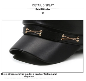 Close-up of black faux leather peaked cap featuring a decorative gold metal cross chain