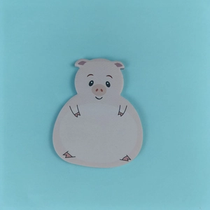 Close-up of cute pink cartoon pig sticky note on a bright blue background for journaling