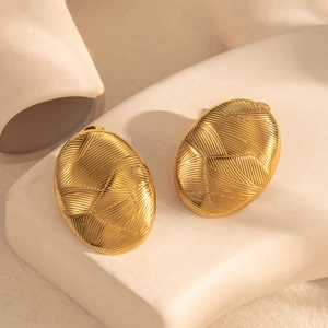 Golden oval stainless steel earrings with elegant striped texture on minimalist display