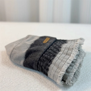 Close-up of grey striped denim texture with frayed edges and brown leather patch