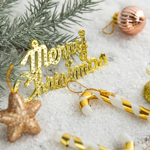 Golden Merry Christmas sign with star and candy cane ornaments on snowy pine branches