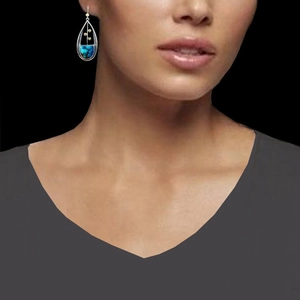 Orecchini pendenti boho in argento con gemma blu-verde indossati su sfondo nero intenso