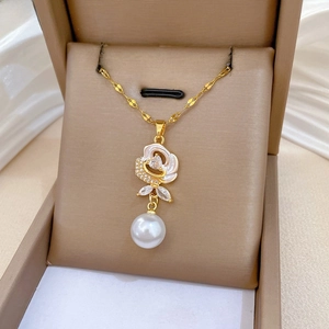 Close-up of elegant rose flower pendant with large white pearl on golden necklace