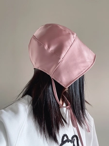 Detail of pink satin bonnet sun hat with adjustable ribbon ties on a female model